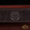 close-up view of american buffalo stamp on dark brown leather belt on wood table