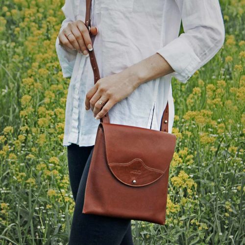 Leather vintage brown Derby handbag on woman in field