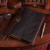 Dark drown buffalo leather composition journal cover on small antique desk with spectacles and antique pen beside it
