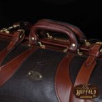 Vintage-style Gladstone dark brown american buffalo leather No. 5 Grip travel bag on wooden table - detail view of handle
