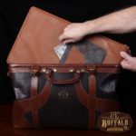 Vintage-style Gladstone dark brown american buffalo leather No. 5 Grip travel bag on wooden table - man putting $50 bill in secret pocket of removable bottom panel