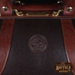 Vintage-style Gladstone dark brown american buffalo leather No. 5 Grip travel bag on wooden table - detail view of American Buffalo stamp