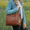 Woman carrying Leather vintage brown Wayfarer handbag in field