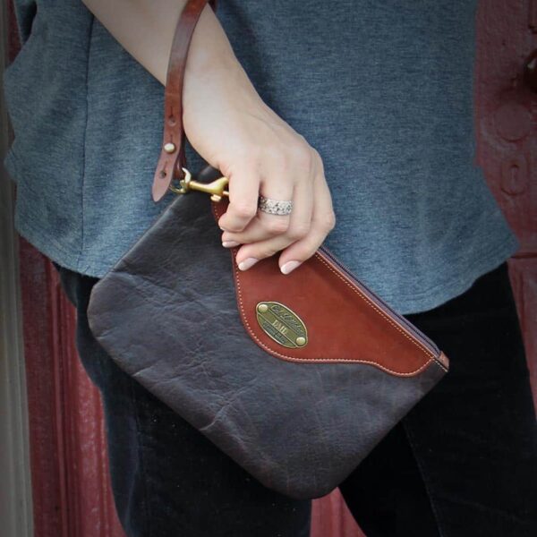 brown leather wristlet clutch held by women's hand