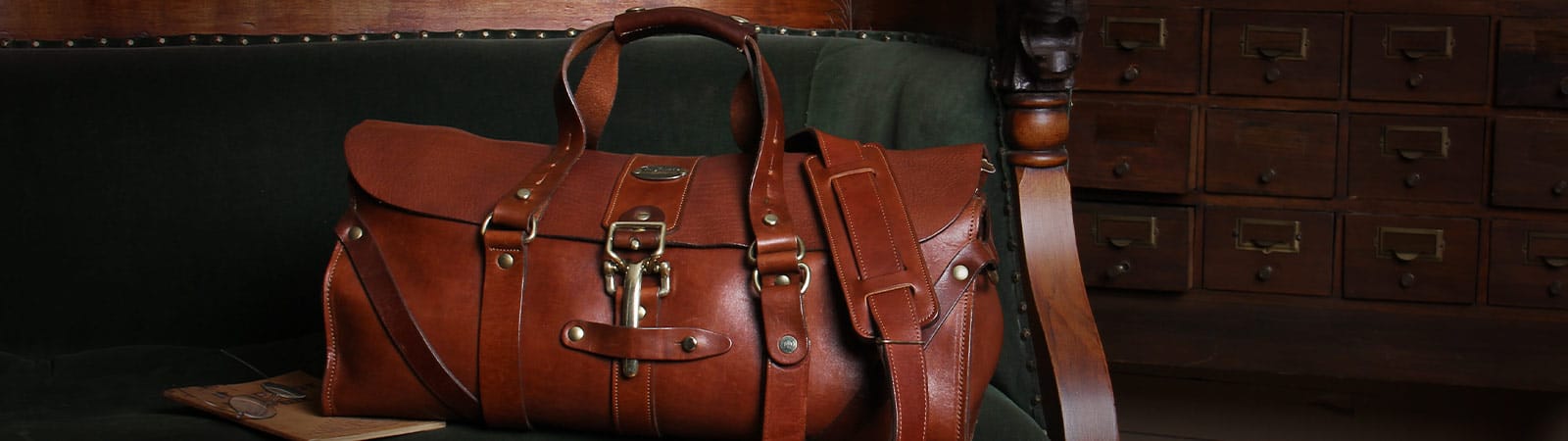 Luggage Category Header - No. 1 Grip travel bag in vintage brown american steerhide sitting on an antique green velvet couch