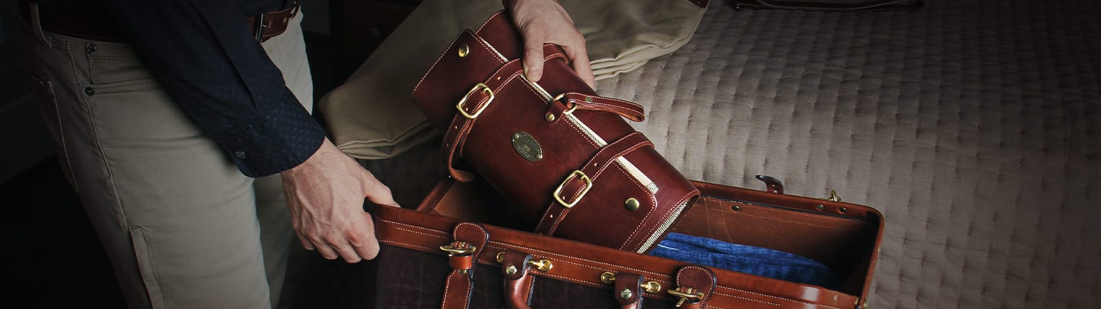 Shave and Dopp Kits Category Header - Man putting Vintage Brown leather No. 2 Shave Kit into a No. 2 Grip travel bag