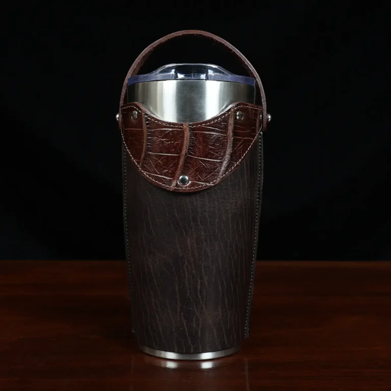 The front view of a leather tumbler sleeve show casing tobacco brown American buffalo and American alligator trim and the stainless steel tumbler insert.