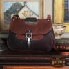 No. 18 Hunt bag in Tobacco Brown American Buffalo with Vintage Brown Steerhide Trim - front view of back resting on antique furniture with books and paintings in the background