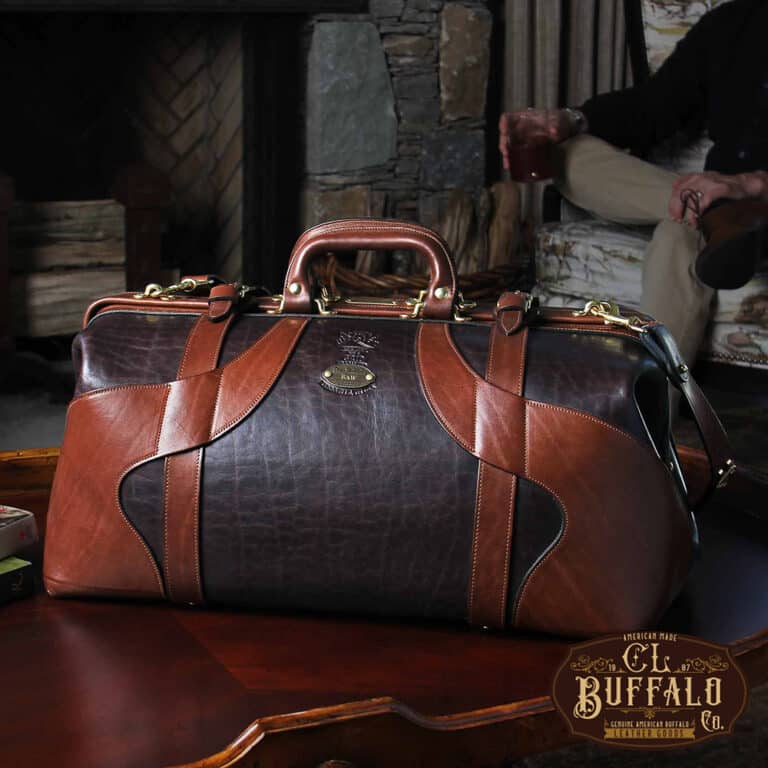 No. 5 Grip in Tobacco Brown American Buffalo with Vintage Brown Steerhide trim - front view of bag resting on antique coffee table in front of stone fireplace