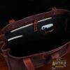 Bentley Tote in dark Tobacco Brown American Buffalo with contrasting vintage brown American Steerhide Trim - view of black canvas inside pockets with papers and a phone