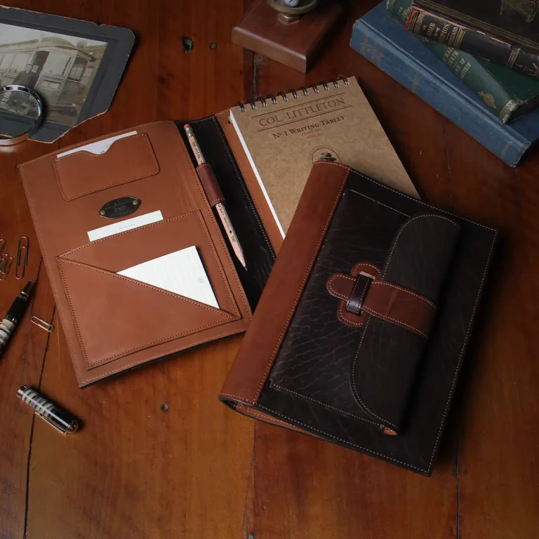 No. 1 Steno Padfolio in Tobacco Brown American Buffalo with Vintage Brown Steerhide Trim - 2 notebooks on a wooden table with the bottom one open and the top one closed