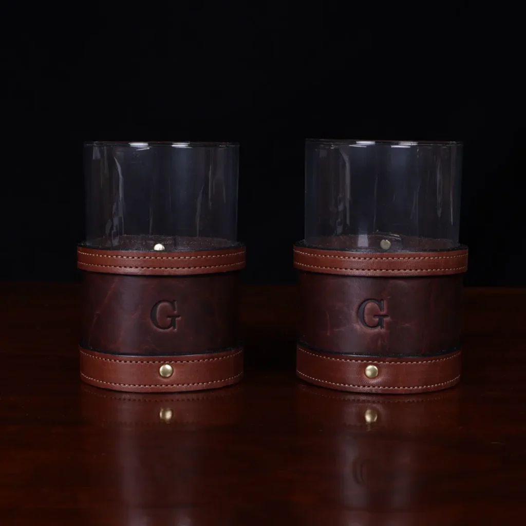 Veranda Glasses in Tobacco Brown American Buffalo with vintage brown steerhide trim - Set of 2 on a wooden table
