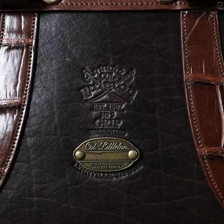 no 5 grip in tobacco buffalo with brown american alligator trim - front view of logo - on a wood table with black background - ID 001