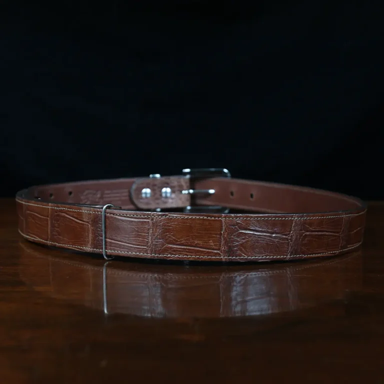 An American Alligator Belt with Nickel hardware showing the back view on a wooden table with black background - id 002