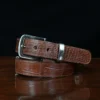 An American Alligator Belt with Nickel hardware showing the front view on a wooden table with black background - id 002