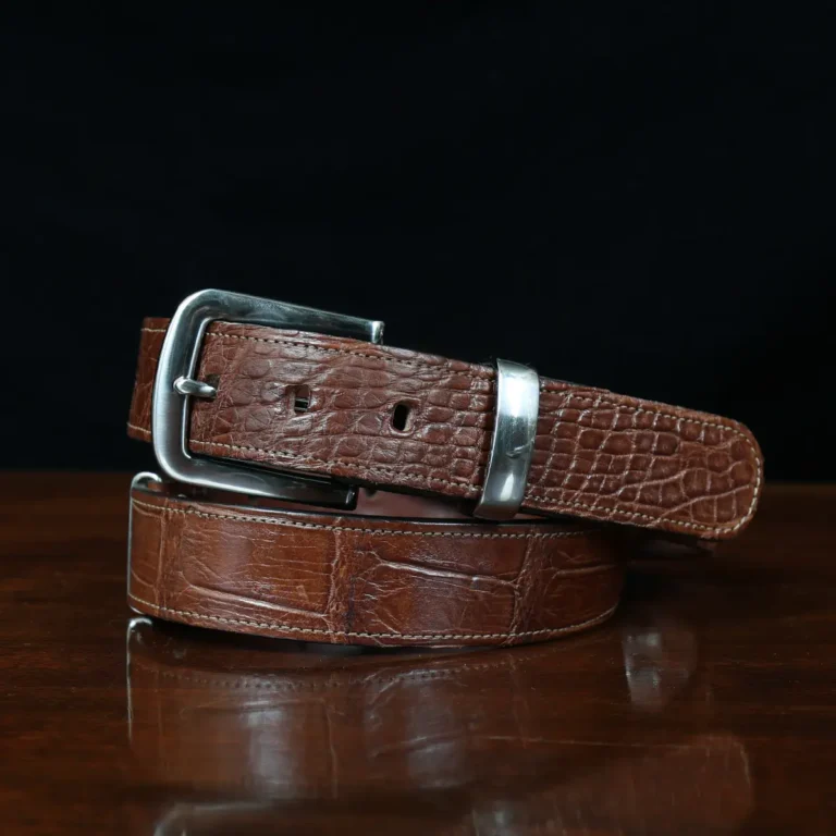 An American Alligator Belt with Nickel hardware showing the front view on a wooden table with black background - id 002