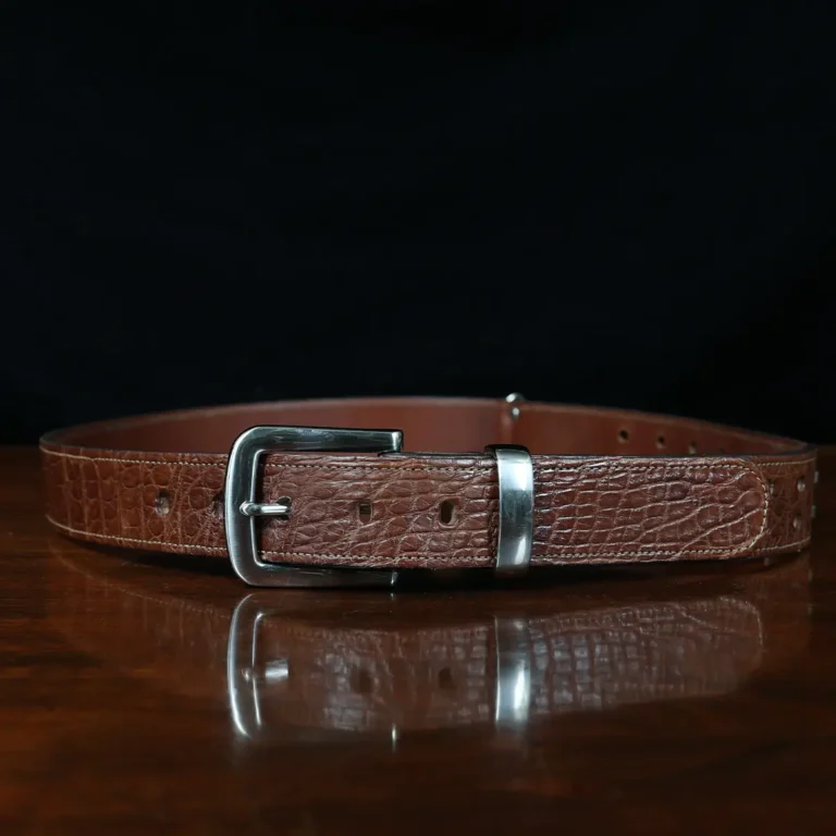 An American Alligator Belt with Nickel hardware showing the front view on a wooden table with black background - id 002