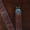 An American Alligator Belt with Nickel hardware showing the open hook view on a wooden table with black background - id 002