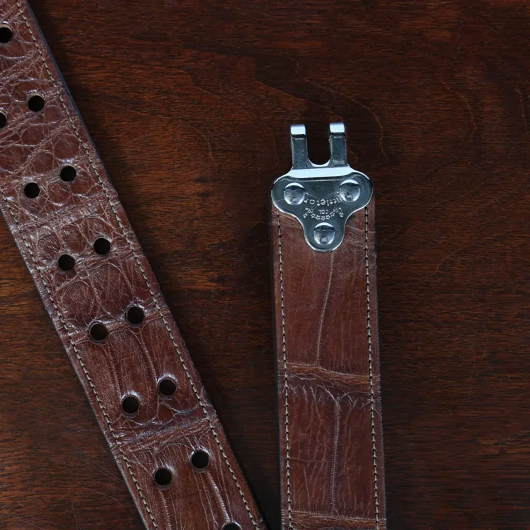 An American Alligator Belt with Nickel hardware showing the open hook view on a wooden table with black background - id 002