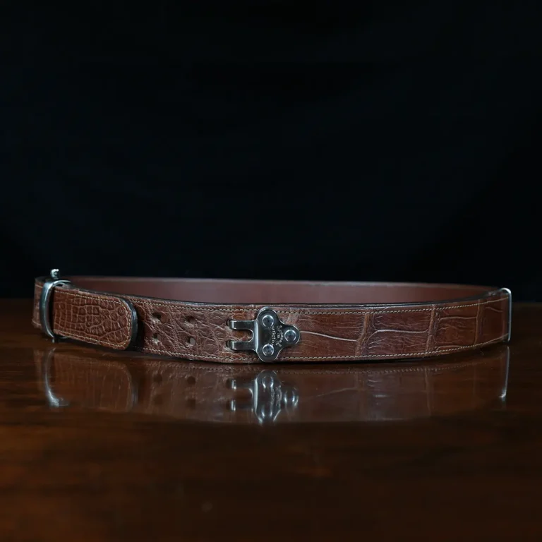 An American Alligator Belt with Nickel hardware showing the side view on a wooden table with black background - id 002