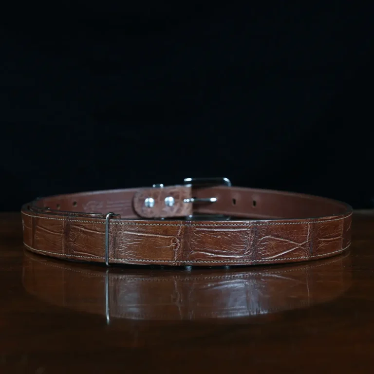 An American Alligator Belt with Nickel hardware showing the back view on a wooden table with black background - id 002