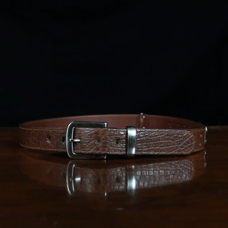 An American Alligator Belt with Nickel hardware showing the front view on a wooden table with black background - id 002