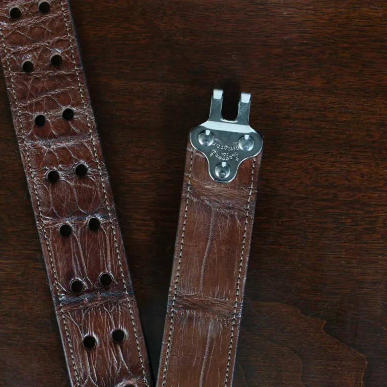An American Alligator Belt with Nickel hardware showing the open hook view on a wooden table with black background - id 002