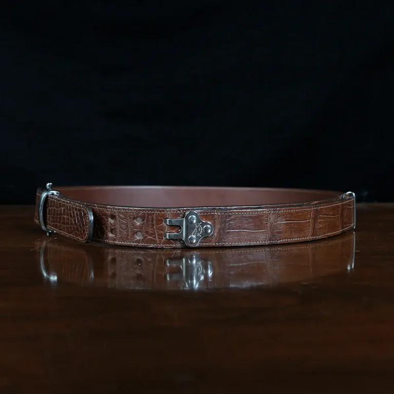 An American Alligator Belt with Nickel hardware showing the side view on a wooden table with black background - id 002