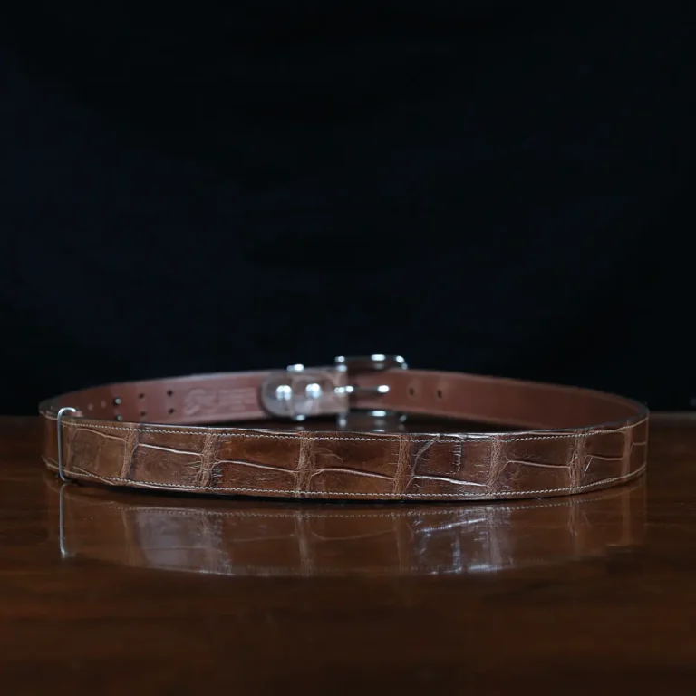 An American Alligator Belt with Nickel hardware showing the back view on a wooden table with black background - id 002