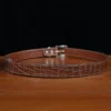 An American Alligator Belt with Nickel hardware showing the back view on a wooden table with black background - id 002