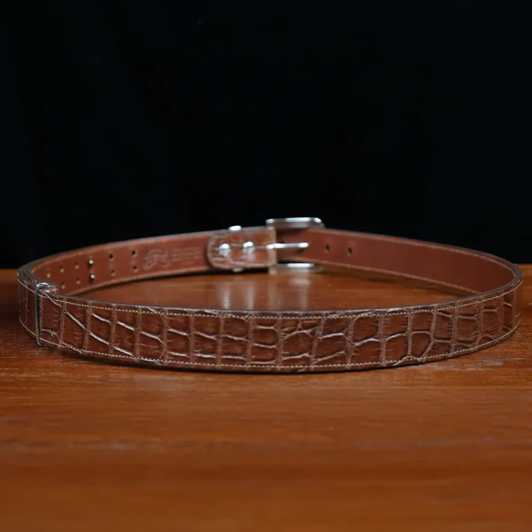 An American Alligator Belt with Nickel hardware showing the back view on a wooden table with black background - id 002