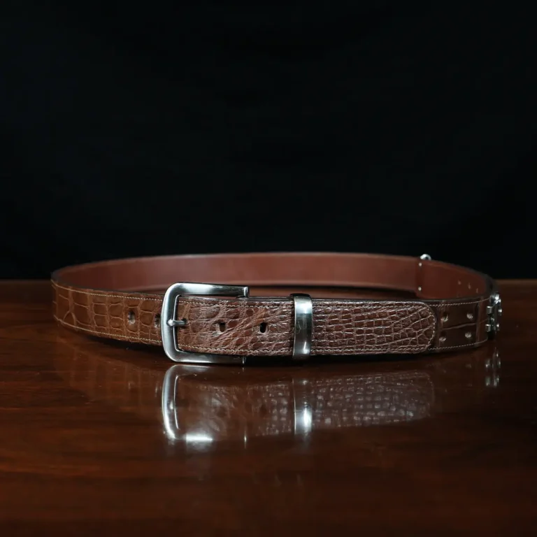 An American Alligator Belt with Nickel hardware showing the front view on a wooden table with black background - id 002