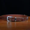 An American Alligator Belt with Nickel hardware showing the front view on a wooden table with black background - id 002