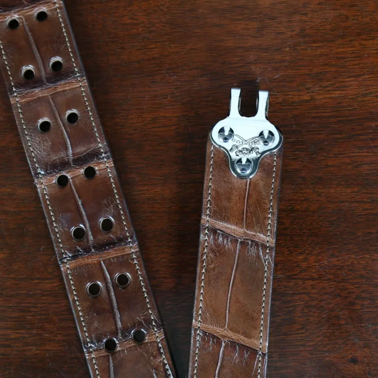 An American Alligator Belt with Nickel hardware showing the open hook view on a wooden table with black background - id 002