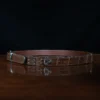 An American Alligator Belt with Nickel hardware showing the side view on a wooden table with black background - id 002