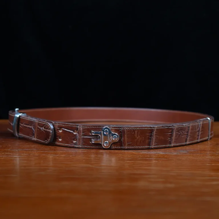An American Alligator Belt with Nickel hardware showing the side view on a wooden table with black background - id 002