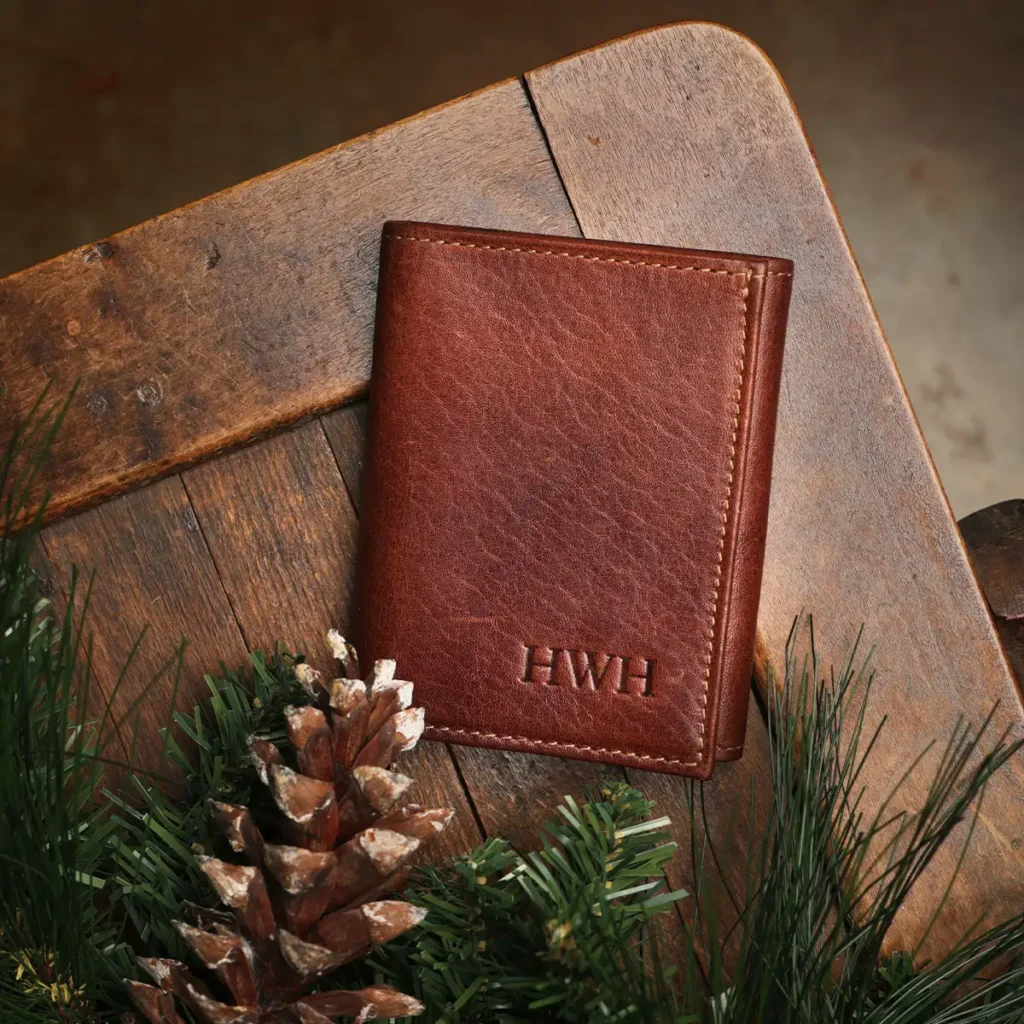 Leather Wallet with pine needles and pine cones on wooden table