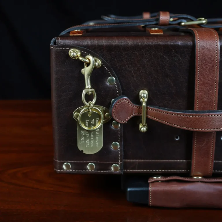 no 3 travel trunk in american buffalo - showing the id tag with a dark background on wood table