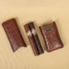 A leather Cigar Case in American Alligator showing the front with leather cigars with brass hardware - id 002