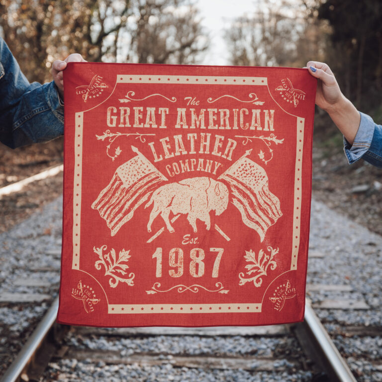 Two people holding onto the Colonel Littleton Bandana in front of a railroad track.