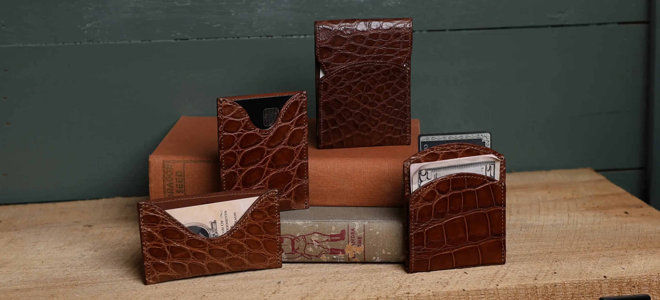 Four American Alligator wallets positioned on books